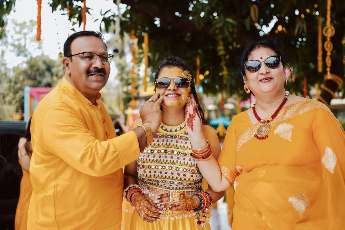 Family members in colourful Indian clothing sharing a joyful outdoor wedding celebration.
